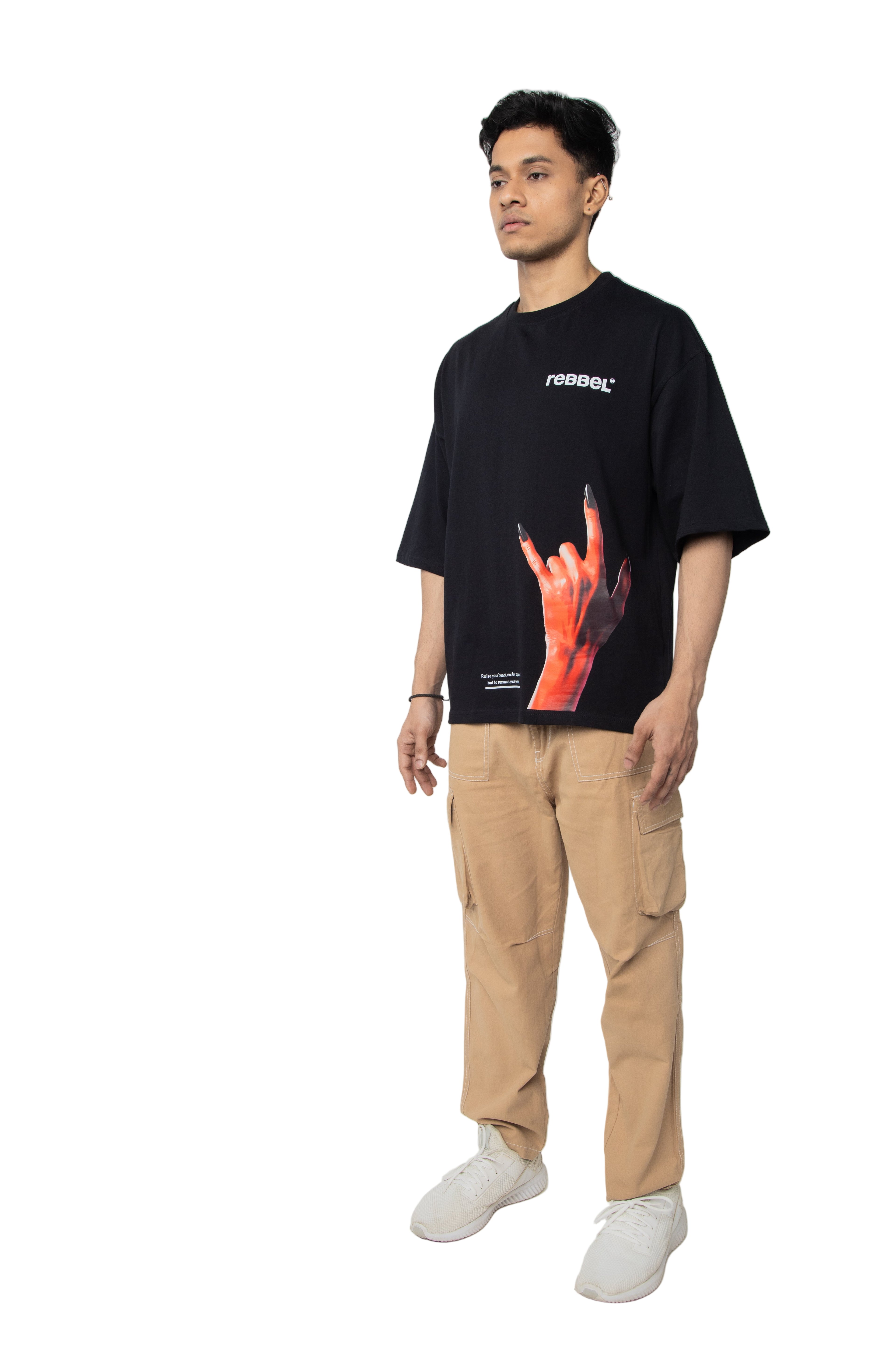 Person wearing a black t-shirt with a graphic design and beige pants on a white background