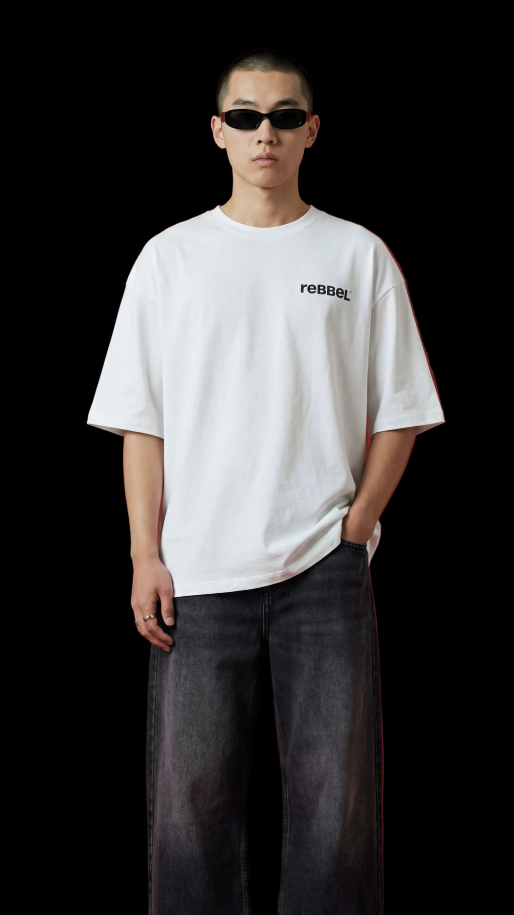 Person wearing a white t-shirt with text and dark jeans against a red background