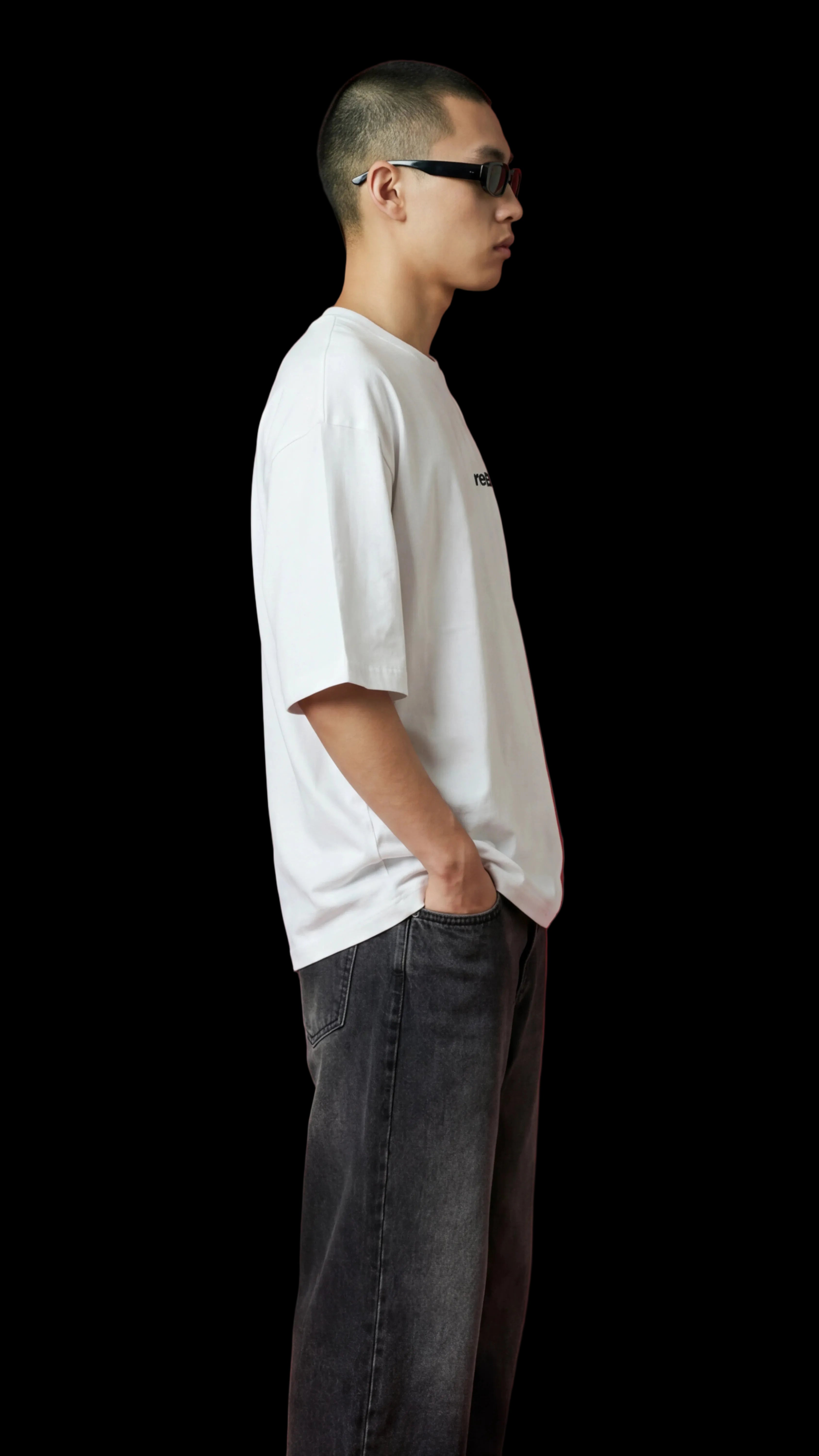 Person wearing a white t-shirt and dark jeans against a red background